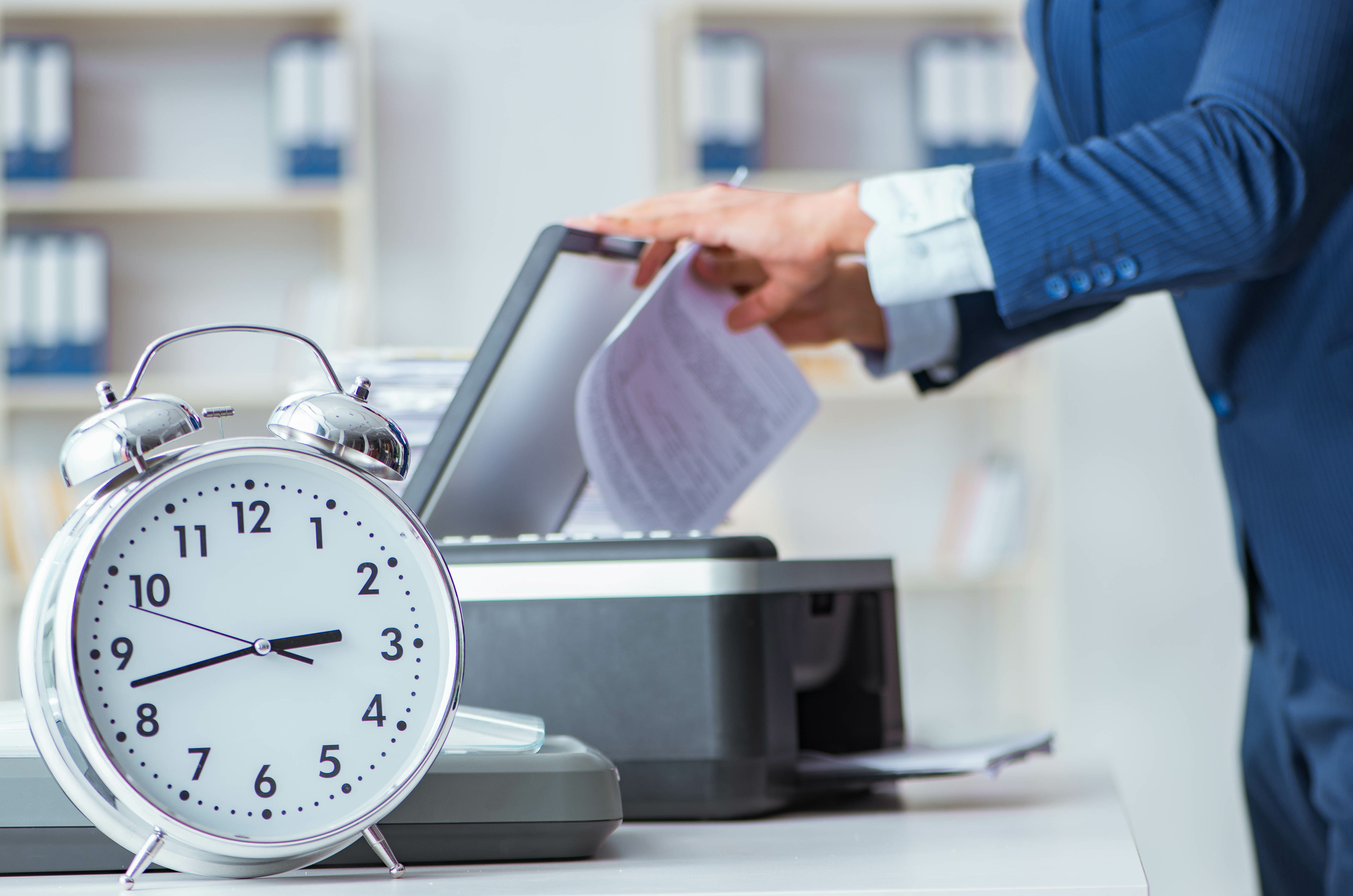 Man using printing with clock in the foreground.